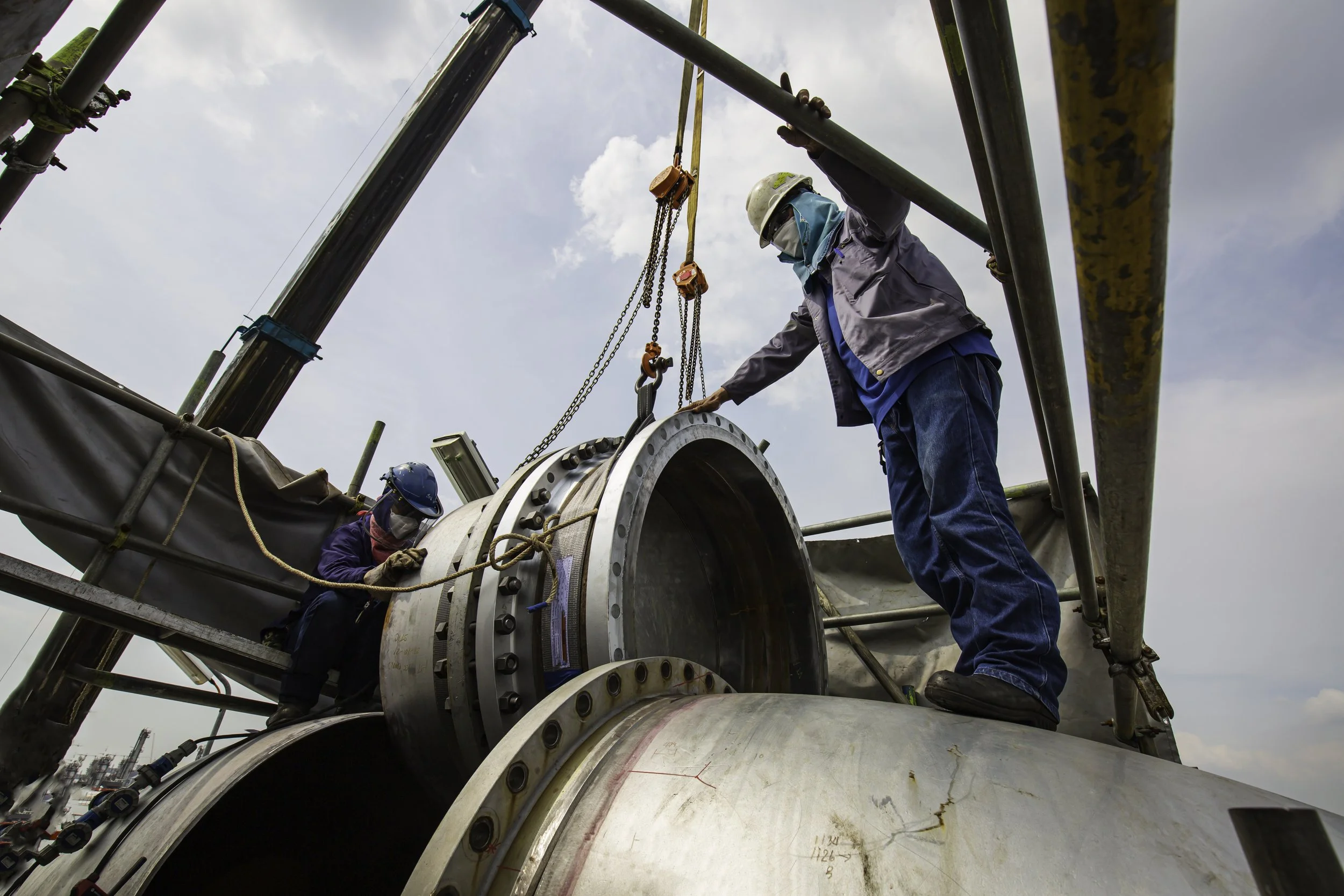 Engineers working on heavy metal pipeline construction and industrial rigging setup